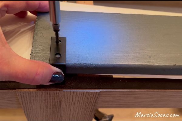 adding an L bracket to a piece of wood to create a shelf