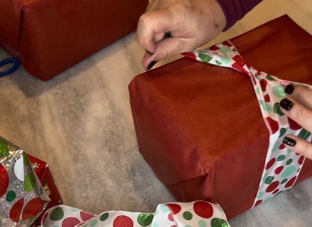 adding christmas ribbon to wrapped boxes